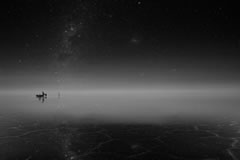 The stars are reflected in the water on the salt flat.